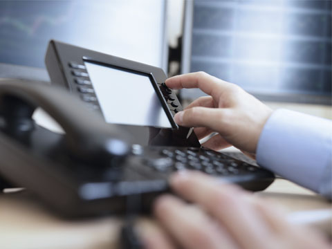 Office worker dialing a phone from a VoIP service provider in Sandy Springs, GA